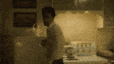 a man in a white shirt stands in a kitchen