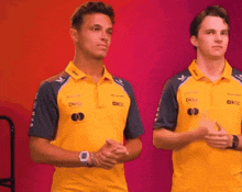 two young men are standing next to each other wearing yellow shirts .