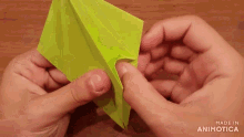 a person is holding a piece of green paper with the words made in animotica on the bottom right