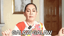 a woman is making a funny face with her hands outstretched and the words galaw galaw written on her chest .