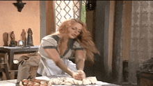 a woman kneading dough with a bag of flour in the background