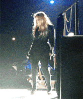 a woman standing on a stage with a microphone in the background