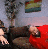 a man with a beard is laying on a couch laughing .