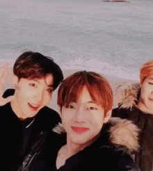 three young men are posing for a selfie on the beach