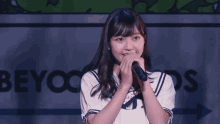 a girl singing into a microphone in front of a sign that says eyoo
