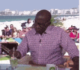 a man in a plaid shirt is sitting at a table with a cup of coffee on it .