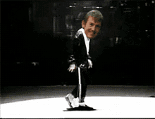 a man in a black suit is dancing on a stage
