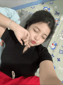 a woman is laying on a bed with a doraemon blanket