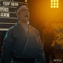 a man in a karate uniform is standing in front of a sign that says netflix .