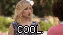 a woman is talking to another woman while holding a sign that says cool .