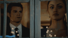 a man and woman are looking out a window
