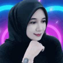 a woman wearing a hijab and a watch looks to the side