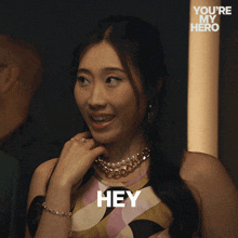 a woman says hey in front of a you 're my hero logo
