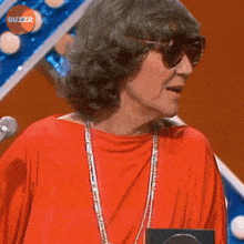 a woman wearing sunglasses and a red top with buzzr written on the bottom