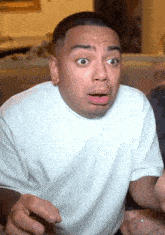 a man in a white t-shirt is making a surprised face