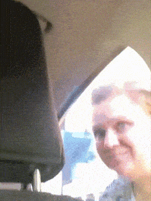 a woman in a car is smiling and looking at the camera