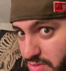 a close up of a man 's face wearing a hat and a beard .
