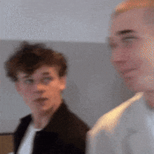 two men are standing next to each other and one is wearing glasses