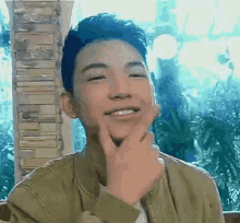 a young man is making a funny face while holding his hand to his chin .