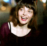 a woman wearing a necklace and a burgundy shirt smiles for the camera