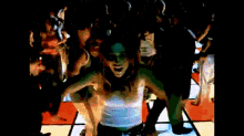 a woman in a white tank top is dancing on a dance floor in front of a crowd