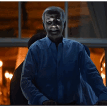 a man in a blue shirt is standing in a dark room