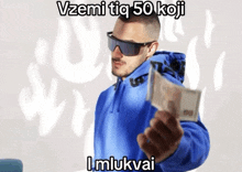 a man wearing sunglasses and a blue jacket is holding a stack of money in his hand