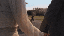 a man and a woman are holding hands while walking down a road