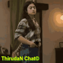 a woman in a plaid shirt is standing in a room with the words thiruda n chat behind her