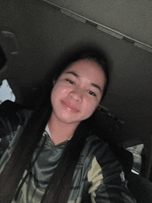 a girl in a car taking a selfie while wearing a hoodie that says the north face