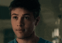 a young man in a blue shirt is smiling and looking at the camera .