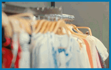 a bunch of clothes are hanging on a rack and one of the shirts says " i love you " on it