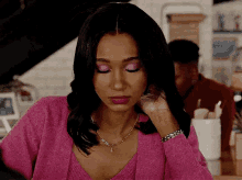 a woman in a pink sweater is sitting at a table .