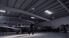 a woman in a black shirt stands with her arms outstretched in a dark room