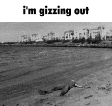 a black and white photo of a man laying on a beach .