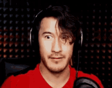 a man in a red shirt is wearing headphones and making a funny face