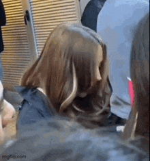 a woman with long hair is sitting in a crowd of people and covering her face .