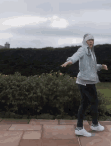 a man in a denim jacket is dancing on a sidewalk