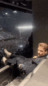 a man is sitting in a stadium with his feet up in front of a large crowd .