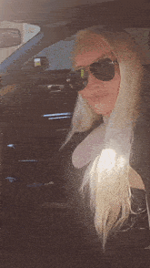 a woman wearing sunglasses sits in a car