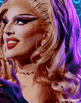 a close up of a drag queen 's face with purple lighting behind her