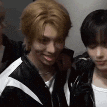 a man with blonde hair is making a funny face while standing next to another man .