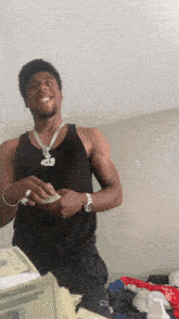a man in a black tank top holds a stack of money