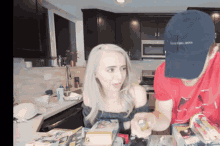 a man wearing a calvin klein hat talks to a woman in the kitchen