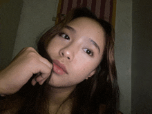 a girl with long hair holds her hand to her mouth