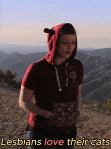 a woman wearing a red hoodie with the words lesbians love their cats
