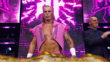 a man in a pink outfit is standing on a stage in front of a pink background .