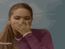a woman in a purple sweater covering her mouth