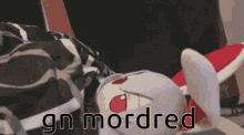 a stuffed animal is laying on a bed with the words " gn mordred " above it