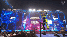 a woman in a wrestling ring is holding a championship while a crowd watches